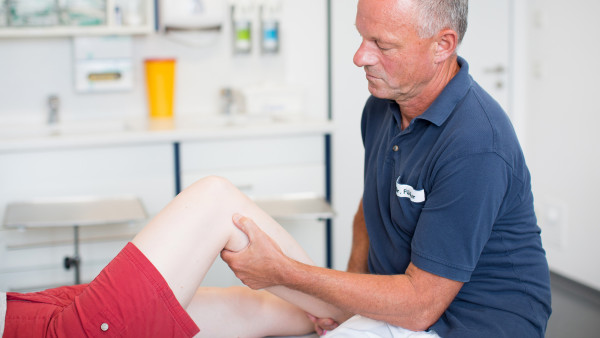 Dr. Jürgen Flicker, Orthopäde und Unfallchirurg untersucht das Bein einer Patientin